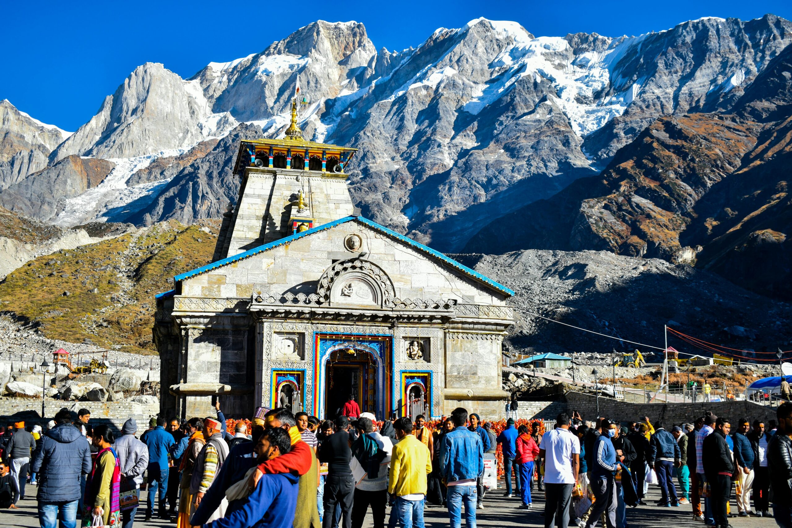 Crowd gathers at केदारनाथ मंदिर Temple with Himalayas backdrop, showcasing religious significance and stunning landscape.